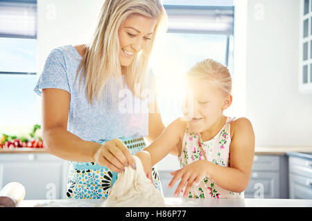 Bambina avendo divertimento aiutare in cucina Imparare a cuocere in forno con la sua amorevole madre come essi impastare insieme b retroilluminato Foto Stock