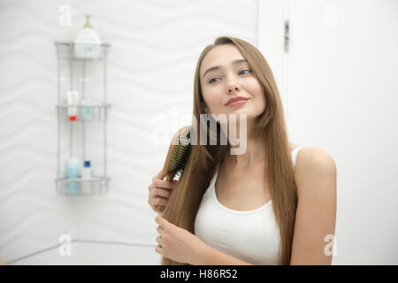 Ritratto di una giovane ragazza sorridente spazzolare i capelli Foto Stock