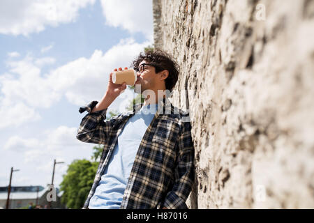 Uomo in occhiali di bere il caffè sulla parete di strada Foto Stock