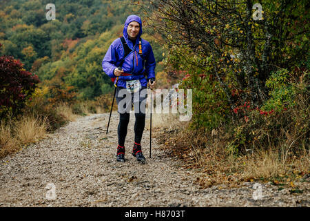 Giovane con walking in esecuzione in tempo piovoso sul sentiero di montagna durante la Crimea maratona di montagna Foto Stock