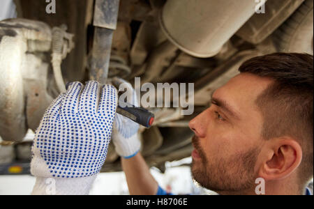 Uomo meccanico con torcia a riparazione auto in negozio Foto Stock