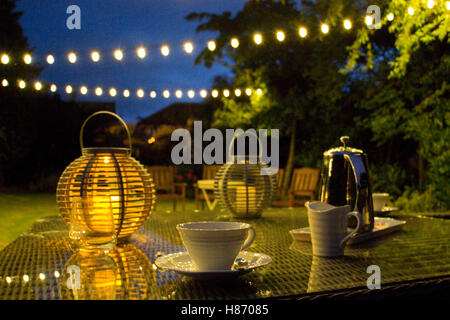 Tarda serata estiva in un giardino inglese con luci decorative Foto Stock