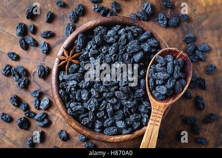 Uva passa nera nella ciotola di legno, vista dall'alto. Snack sani, prodotto dietetico per una buona qualità della vita Foto Stock