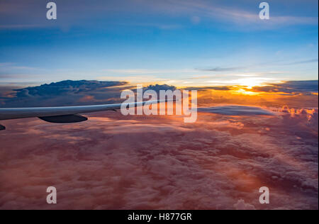 Guardando dalla finestra per aereo ala in volo , con uno splendido scenario di incredibili formazioni di nubi sul Cielo di tramonto Foto Stock