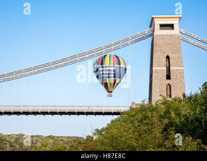 Una mongolfiera cadere dietro il ponte sospeso di Clifton a Bristol Regno Unito durante un volo la mattina presto Foto Stock