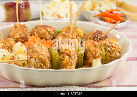 Le polpette di carne su bastoni in una piastra con verdure Foto Stock