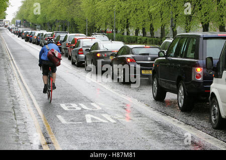 Ciclista traffico passante in ora di punta Foto Stock