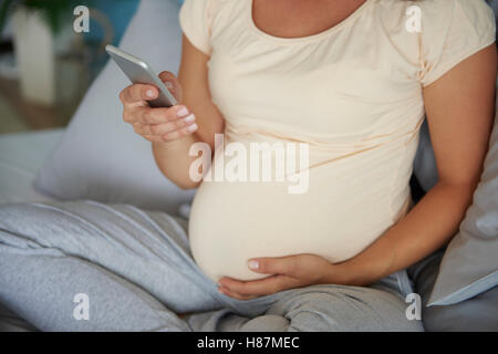 Donna incinta chiacchierato al telefono Foto Stock