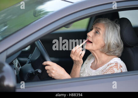 Donna mettendo il rossetto in auto Foto Stock