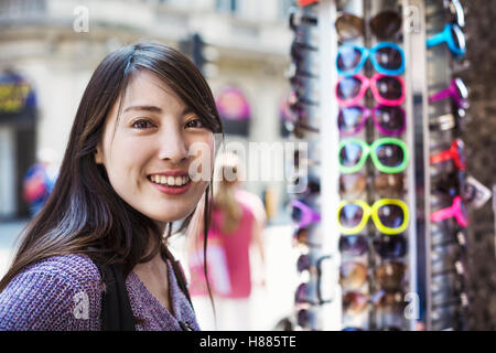 Una donna giapponese cercando su occhiali da sole a Londra, turismo estivo di visitatore. Foto Stock