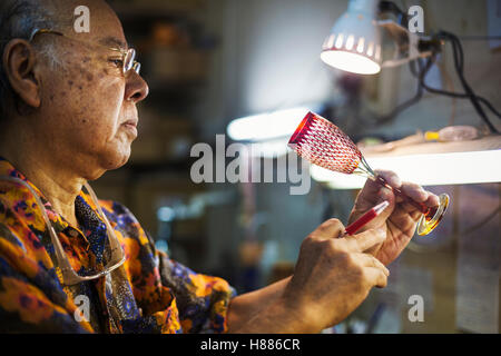 Un senior artigiano al lavoro in un vetro maker's studio workshop. Foto Stock