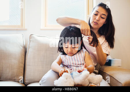 Casa di famiglia. Una madre pettinatura di sua figlia di capelli. Foto Stock