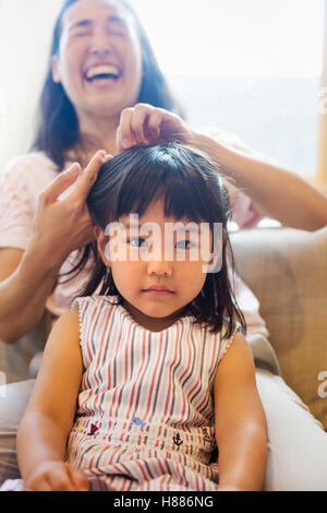 Casa di famiglia. Una madre pettinatura di sua figlia di capelli. Foto Stock