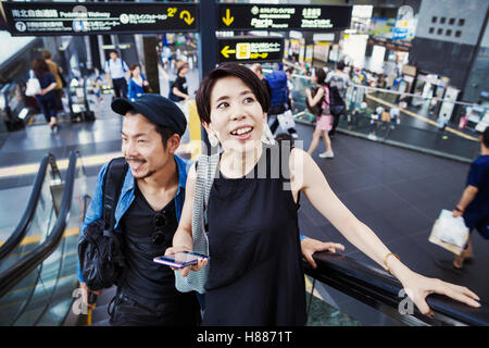 Due persone, l uomo e la donna in sella alla scala mobile in corrispondenza di un centro commerciale per lo shopping. Foto Stock