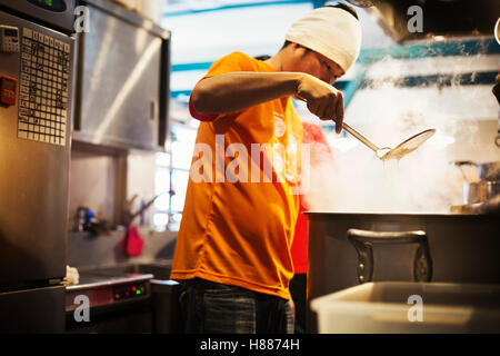 Il ramen noodle shop. Il personale nella preparazione degli alimenti in un vapore riempito la cucina. Foto Stock