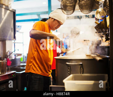 Il ramen noodle shop. Il personale nella preparazione degli alimenti in un vapore riempito la cucina. Foto Stock