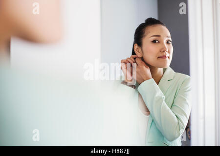 Una donna d'affari in preparazione per il lavoro, spogliatoio e mettendo in gioielleria. Foto Stock