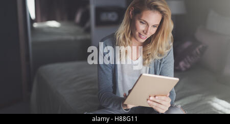 Bella donna bionda utilizzando tablet a casa Foto Stock