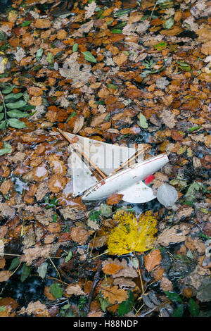 Abbandonato il vecchio stagno vintage yacht su un lago coperto di foglie di autunno Foto Stock