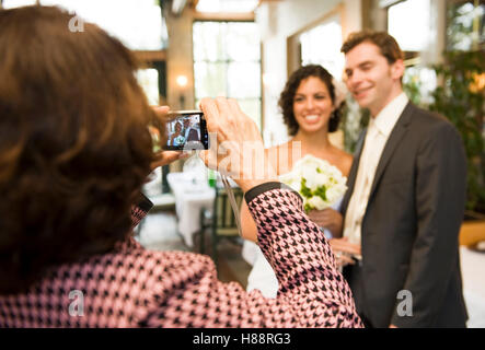 Le donne con fotocamera digitale facendo una foto delle coppie in viaggio di nozze Foto Stock