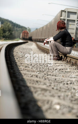Giovane donna seduta su un binario ferroviario Foto Stock