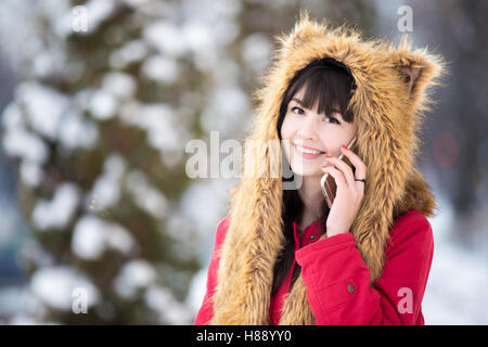 Giovane donna in posa con lo smartphone all'aperto nella stagione invernale Foto Stock