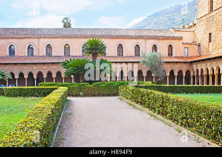 I cespugli tagliati e lussureggianti palme nel giardino del chiostro di Monreale, sicilia, Italia Foto Stock