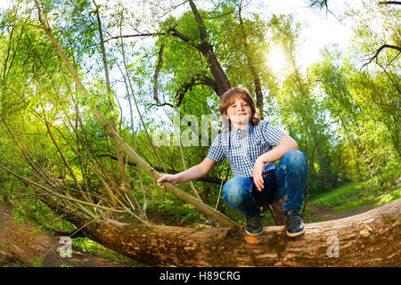 Ragazzo carino sul tronco di albero caduto in posizione di parcheggio Foto Stock
