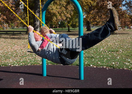 Detroit, Michigan - Adam Hjermstad oscilla con il suo due-anno-vecchio figlio Adam Hjermstad Jr. ad un parco giochi su Belle Isle. Foto Stock