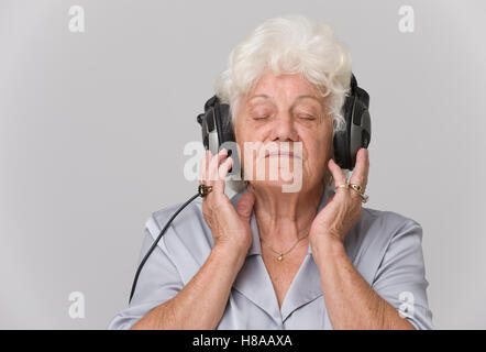 Senior donna con le cuffie per ascoltare musica Foto Stock