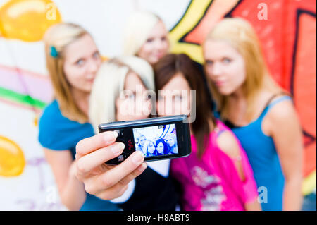 Un gruppo di ragazze adolescenti con un telefono cellulare dotato di fotocamera digitale Foto Stock