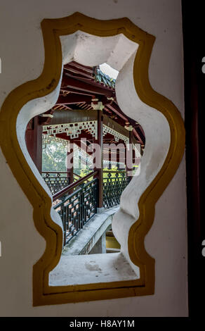 Vista attraverso la finestra a Cinese ponte coperto in giardini su Jiangxin isola nel fiume Ouijang da Wenzhou city in Cina. Foto Stock