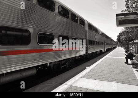 Treno lungo con striscia rossa in corrispondenza della piattaforma in bianco e nero Foto Stock