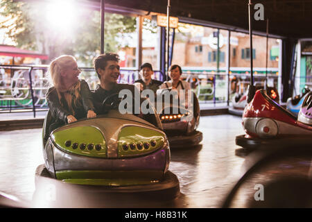 I giovani la guida bumper car alla fiera. Giovani amici divertendosi in sella bumper car al parco divertimenti. Foto Stock