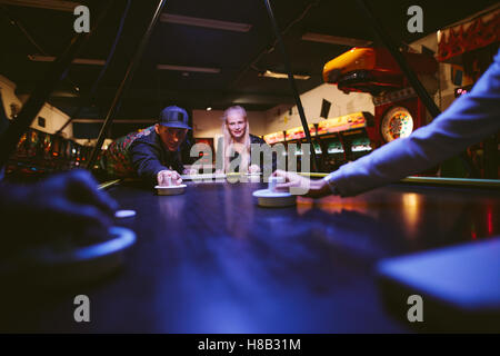 Giovane uomo e donna che gioca a air hockey gioco al parco divertimenti. Giovani divertendosi tabella air hockey. Foto Stock