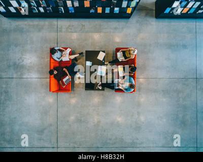 Vista dall'alto di studenti universitari seduto in una biblioteca con libri e computer portatile. I giovani che studiano insieme al college library. Foto Stock