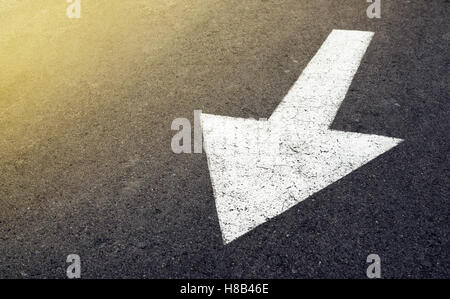 Freccia bianca sulla strada asfaltata, segno di traffico marcatura sulla carreggiata Foto Stock