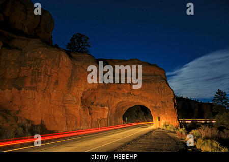 Un auto della striatura luci attraverso un piccolo tunnel in un rosso roccia affiorante sulla Scenic Byway 12 in rosso Canyon vicino a Panguitch USA Utah Foto Stock