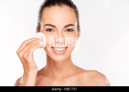Giovane bella pulizia viso con tamponi di cotone isolato su uno sfondo bianco Foto Stock