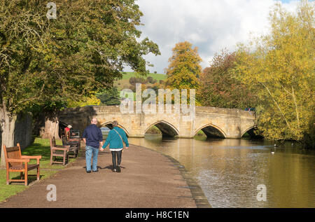 Coppia di anziani a piedi lungo il sentiero lungo il fiume Bakewell, Derbyshire, England, Regno Unito Foto Stock