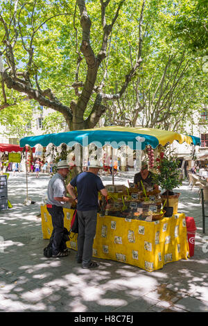 La gente ad una produzione locale di mercato in stallo Place aux Herbes nel borgo medievale di Uzès, Gard, Francia Foto Stock