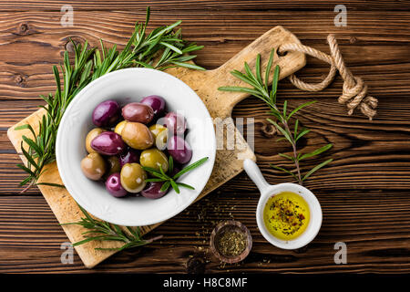 Il cibo italiano ingredienti, rosmarino, olive, olio d'oliva su sfondo di legno Foto Stock