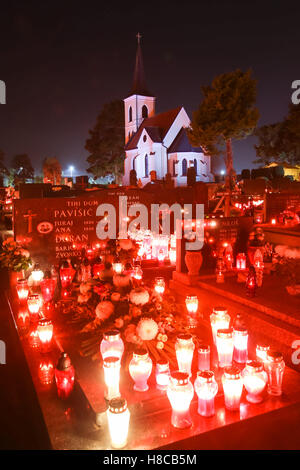 Una vista notturna di tombe ornate con ardente lampions e una chiesa in background sul giorno di Tutti i Santi nella Velika Gorica, Croazia. Foto Stock