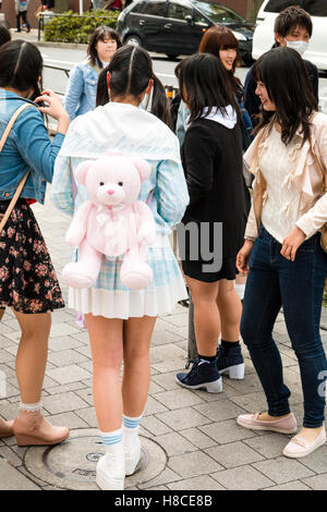 Giappone, Tokyo Harajuku. Vista posteriore di Lolita moda stile kawaii ragazza giapponese in piedi a parlare con gli amici. Sul retro, rosa teddy-bear zaino. Foto Stock