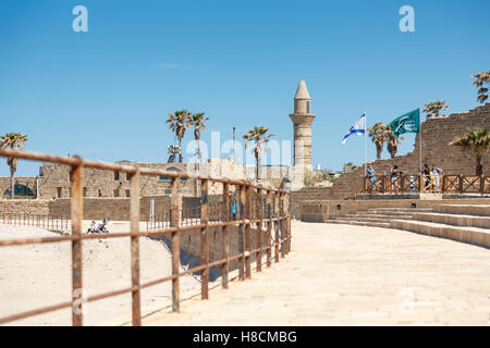 Cesarea, Israele - Aprile 2, 2016: la gente camminare su un mare costa tra antichi resti di Ceasarea in Maritima Parco Nazionale in Foto Stock