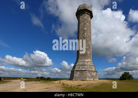 Hardy's Monument torreggianti in alto sulla collina di Blackdown con lone ciclista con cielo drammatico e cloudscape Foto Stock