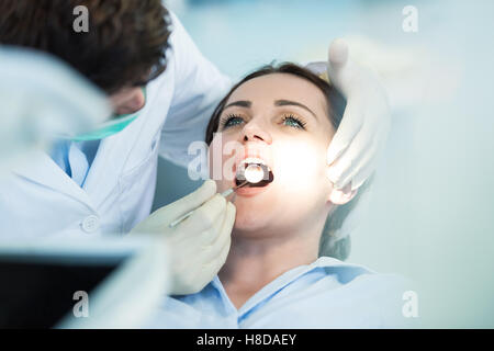Dentista esaminando i denti del paziente con una bocca specchio. Foto Stock