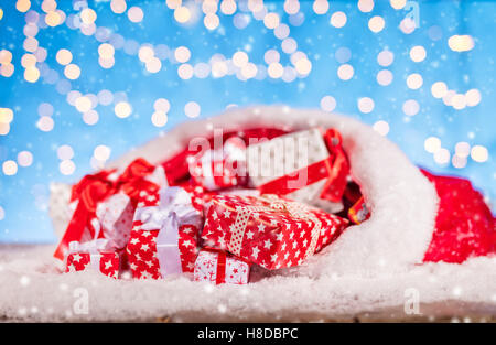 Sfondo di natale con la pila di doni in Santa borsa, collocato sulla neve Foto Stock