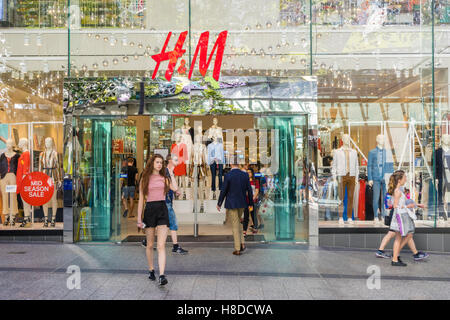 Giovane donna camminare al di fuori di un negozio di abbigliamento a Brisbane Foto Stock