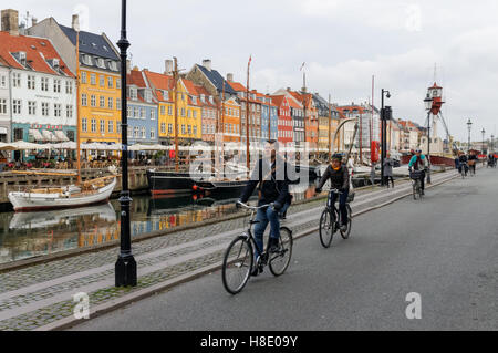 I ciclisti in sella lungo Nyhavn canal a Copenhagen, Danimarca Foto Stock